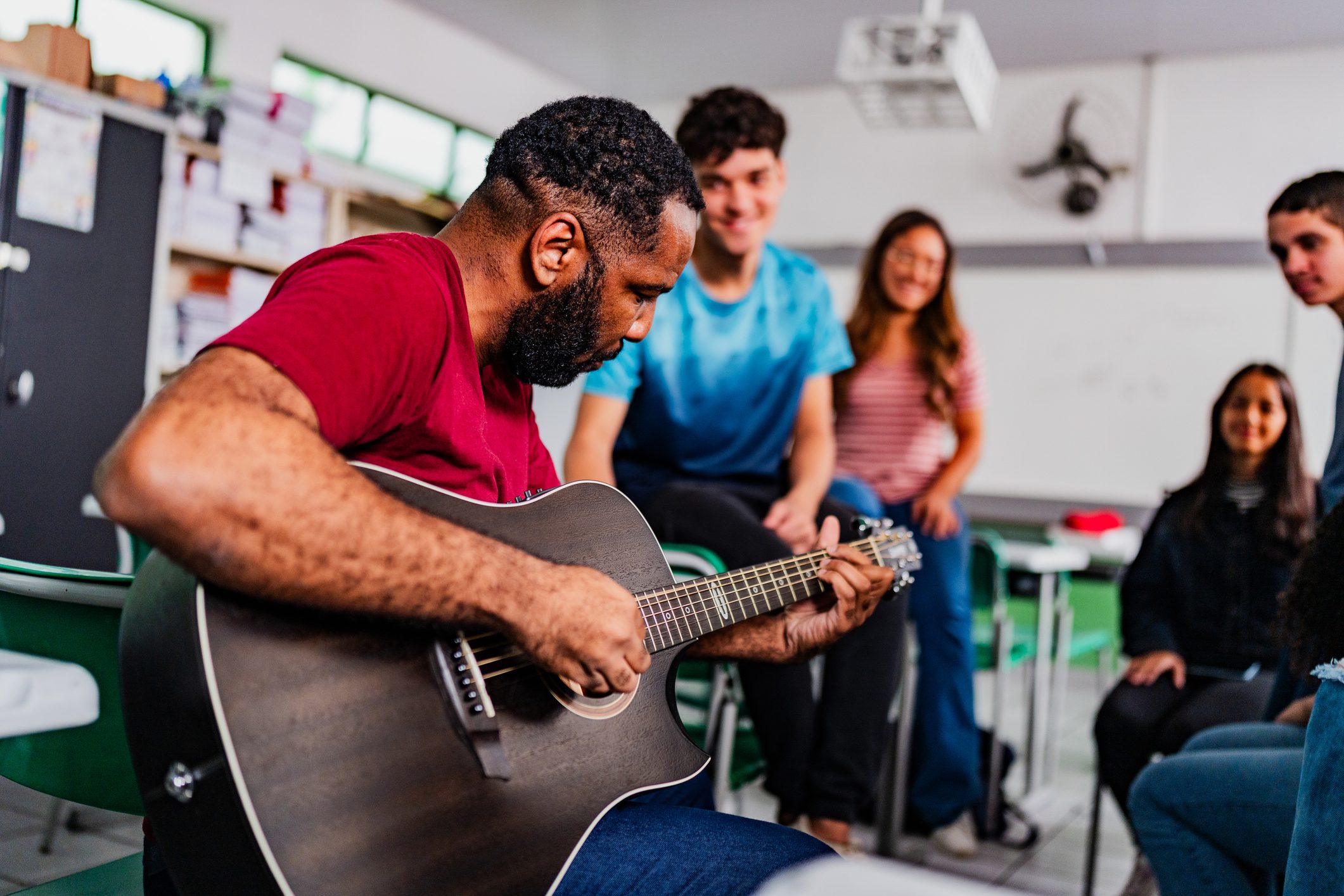 Person playing guitar for students in classroom