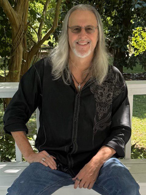 Smiling person with long hair and glasses