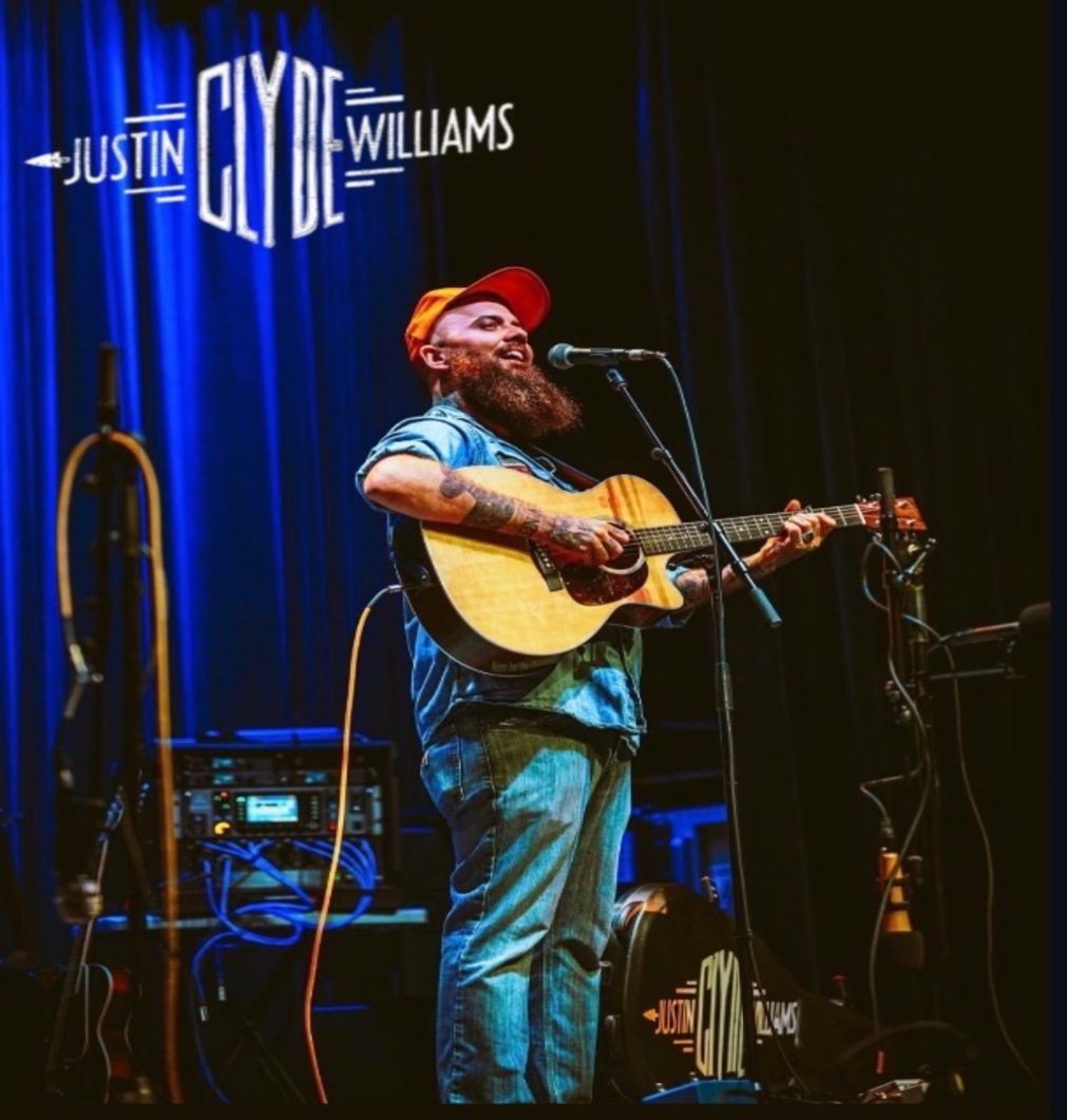 Bearded musician on stage with acoustic guitar