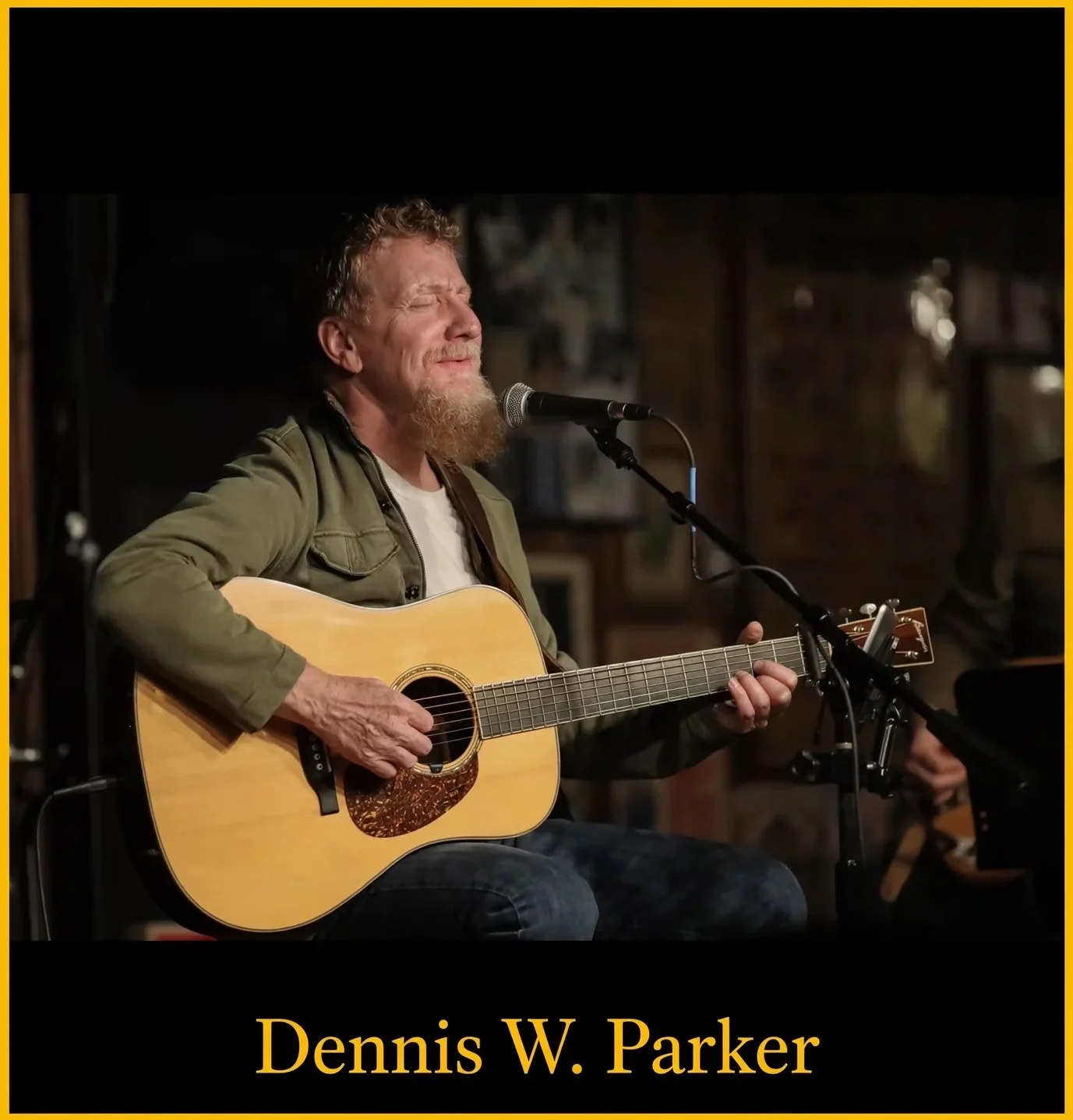 Bearded man singing and playing acoustic guitar
